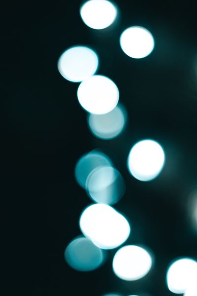 Blue-hued abstract bokeh lights on a dark ground — photo by Athena Sandrini on Pexels