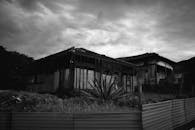 一座废弃的老房子，在戏剧性的多云天空下，以黑白影像呈现