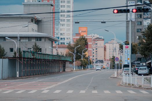 City street with modern buildings and red traffic lights, showcasing an empty urban scene.