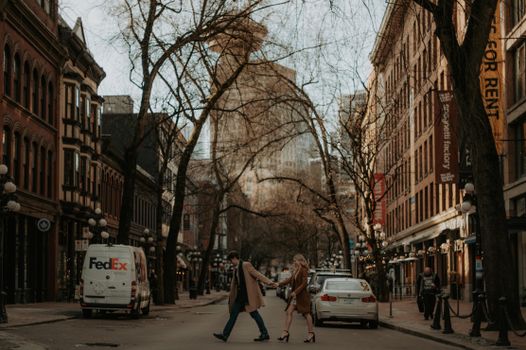 Couple crossing a street in a stylish urban setting, wearing fashionable coats.