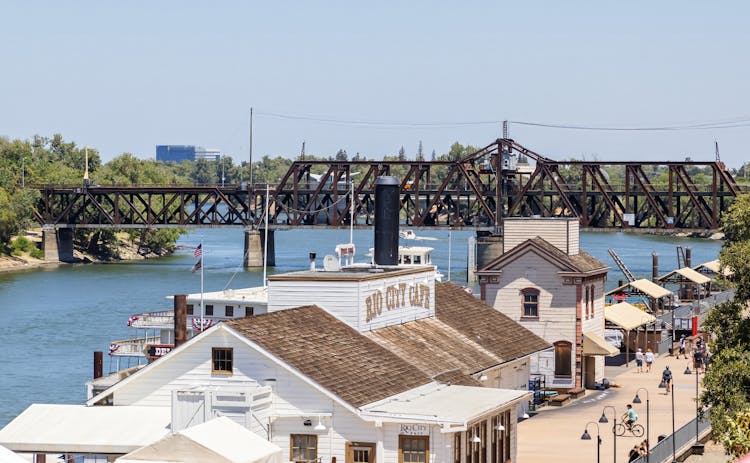 People Walking On Boardwalk With Shops 