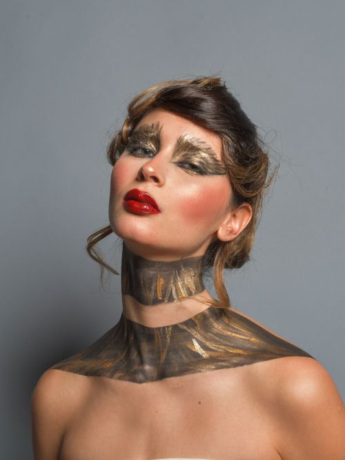 Free Stunning portrait of a woman with striking gold and red makeup against a gray background, showcasing modern artistic flair. Stock Photo