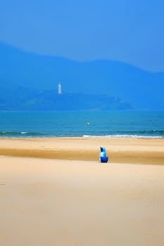 A tranquil beach scene with golden sand, distant mountains, and ocean waves, perfect for relaxation themes.