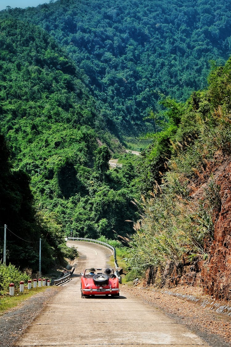 Convertible Car Driving On Road In Mountains Landscape