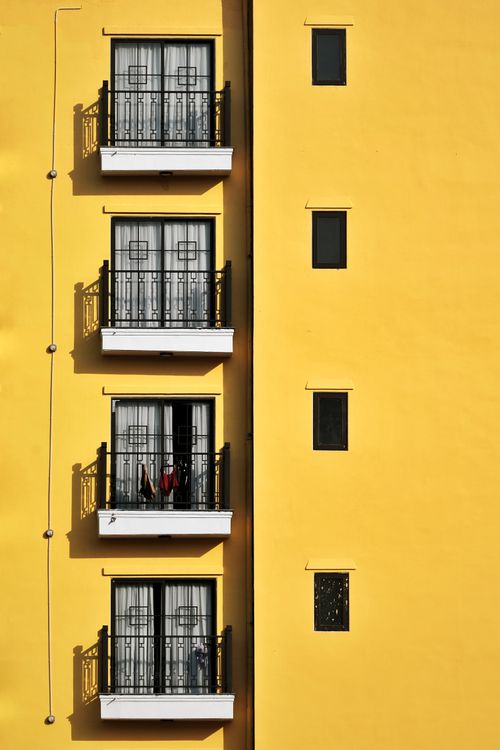 Free Vibrant yellow building facade showcasing symmetrical balconies and modern design. Stock Photo