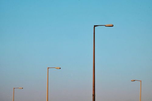 Free Minimalist photo of streetlights silhouetted against a clear blue sky in the evening. Stock Photo