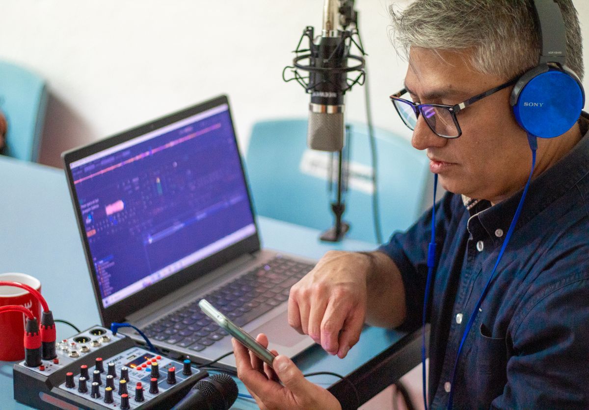 Host with headphones at a laptop and small mixer