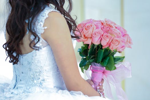 Bride in white dress holding pink roses, perfect for wedding themes.
