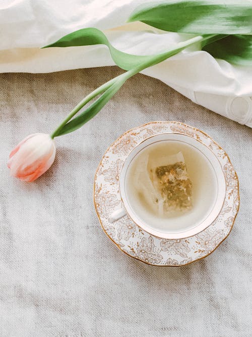 茶杯和茶碟附近的粉紅色花瓣的花朵