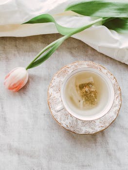 粉红色郁金香旁的花瓷杯里，盛着凉茶，构成了一幅精致的茶场景