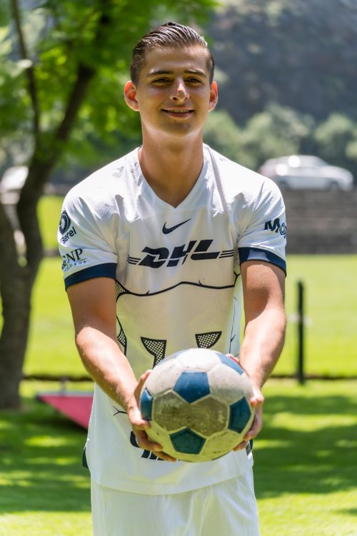 Free Smiling young male in soccer jersey holding a soccer ball outdoors in a sunny park. Stock Photo
