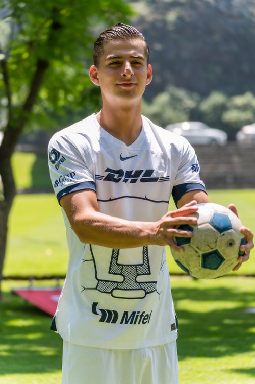 Free A young male soccer player in sportswear holding a ball in a sunny outdoor setting. Stock Photo