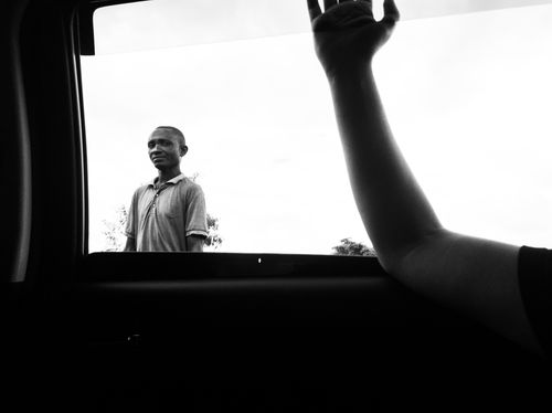 Free A striking black and white image of a man standing outside a car window in Dodoma, Tanzania. Stock Photo