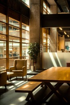 A contemporary café featuring wooden tables, chairs, and large windows with natural light streaming in.