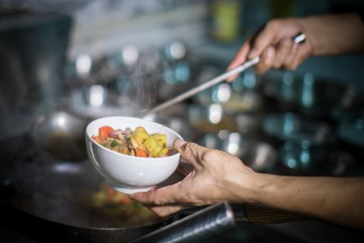A chef skillfully prepares a fresh vegetable stir-fry in a bustling kitchen.