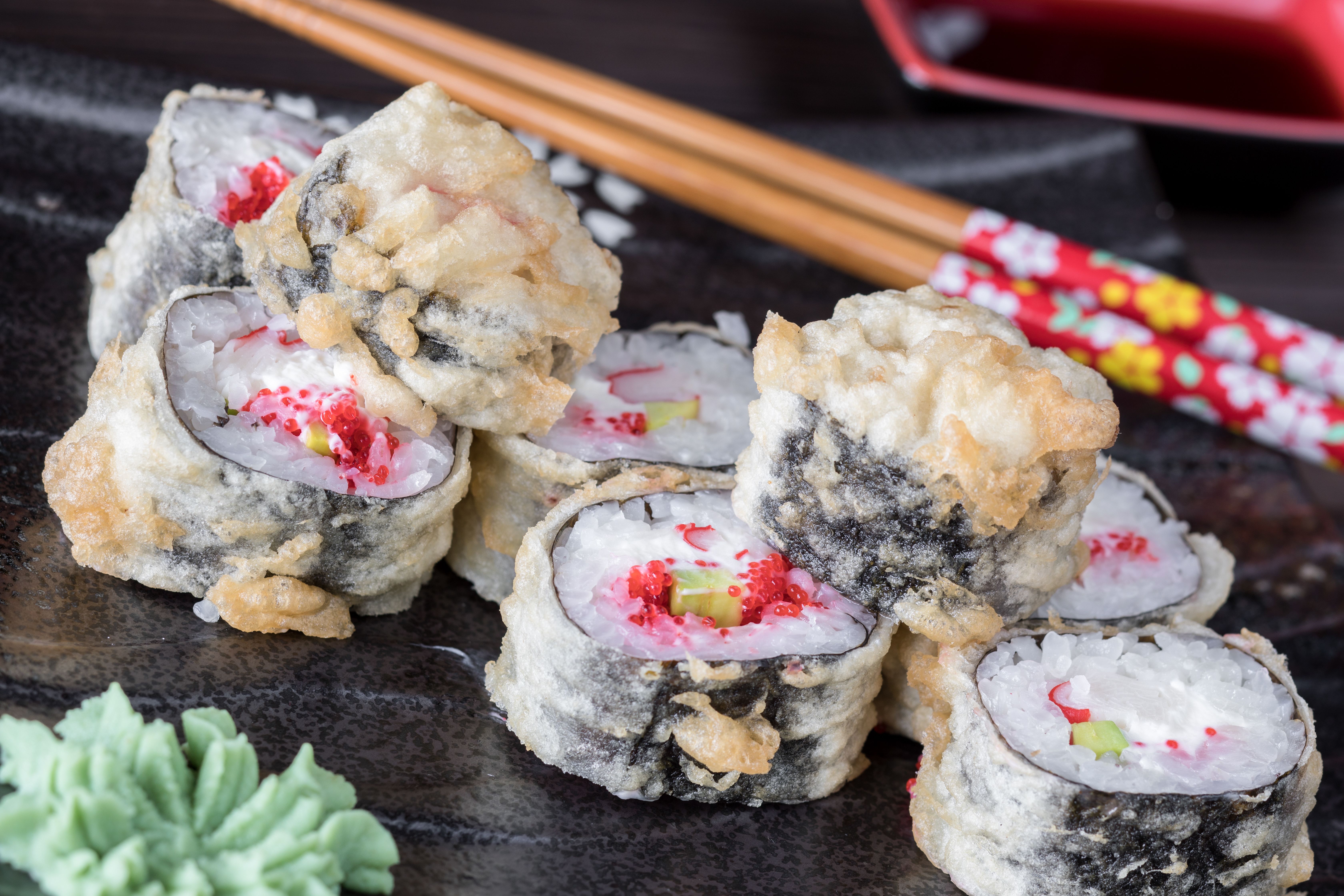 Close-up of crispy tempura sushi rolls served with wasabi and decorative chopsticks in Istanbul.