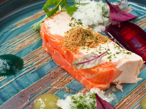 Free A close-up of gourmet salmon served with herbs and colorful garnish on a decorative plate. Stock Photo