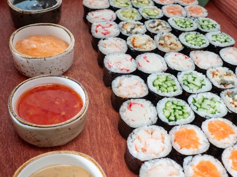 An appetizing display of sushi rolls with different fillings accompanied by dipping sauces.