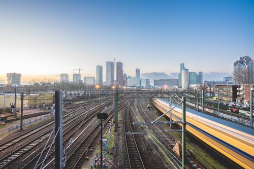 Free Railway tracks leading to Den Haag cityscape at dusk, showcasing urban transportation. Stock Photo