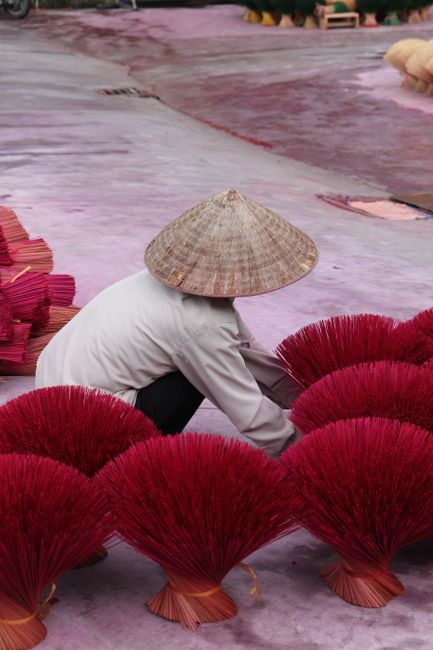 A person arranging incense sticks in Hanoi, Vietnam, showcasing traditional craftsmanship.
