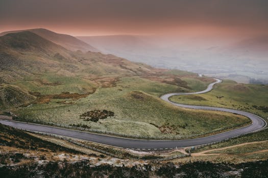 黄昏时分，蜿蜒的道路穿过雾蒙蒙的山景，构成了一幅戏剧性的鸟瞰图