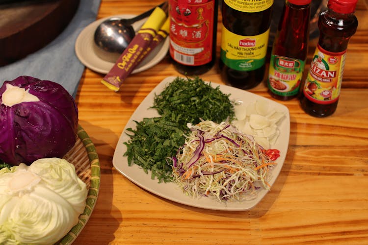 White Plate With Fresh Salad Ingredients And Sauce Bottles On A Table