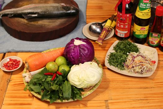 An assortment of fresh vegetables, herbs, and fish ready for a traditional Asian culinary preparation.