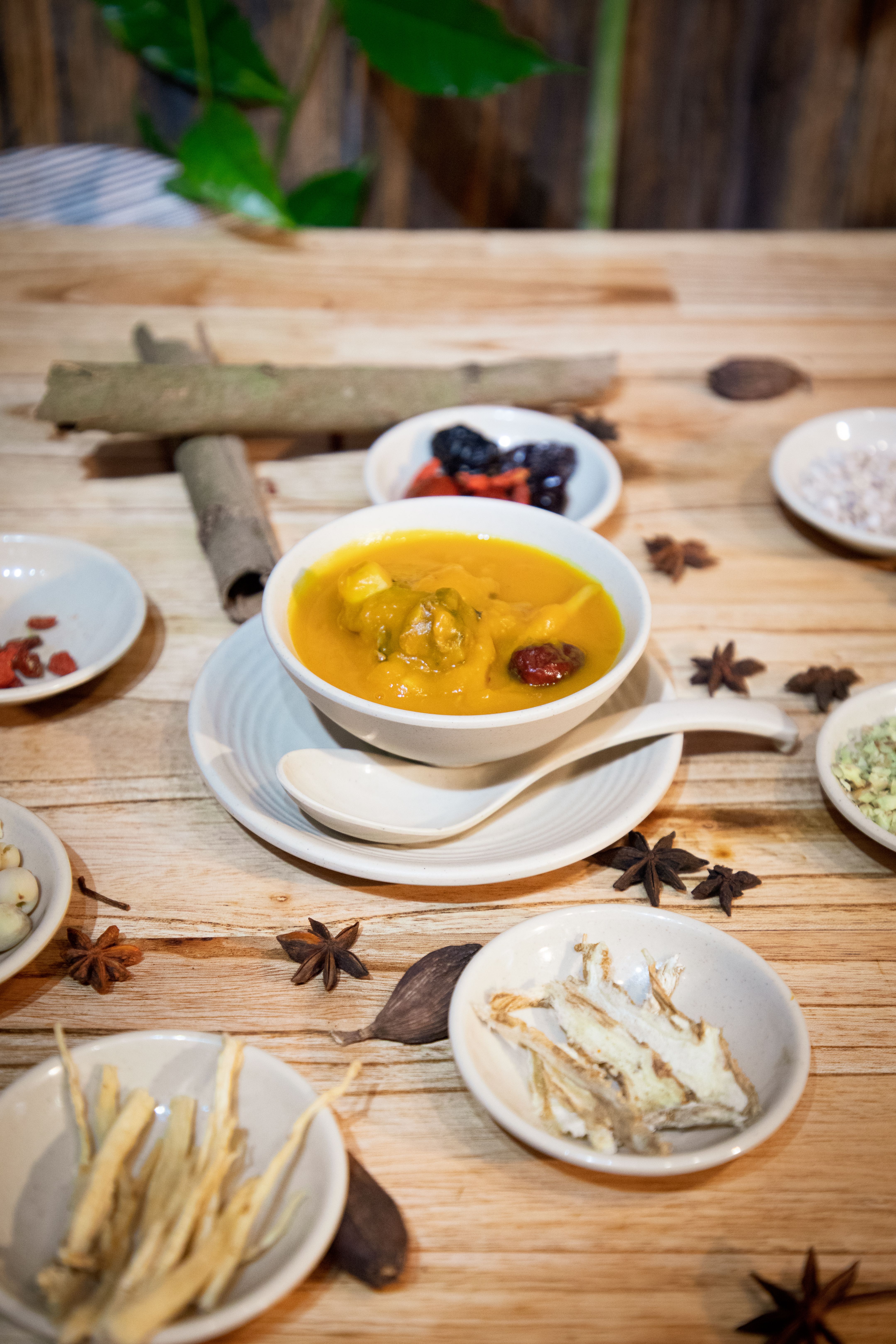 Delicious pumpkin soup with Asian herbs and spices on a rustic wooden table.