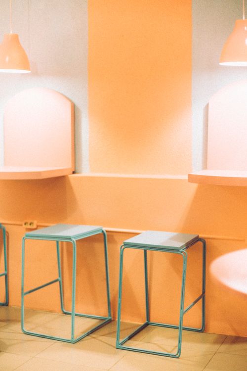 Free Chic café interior with orange walls, modern stools, and soft lighting for a cozy ambience. Stock Photo