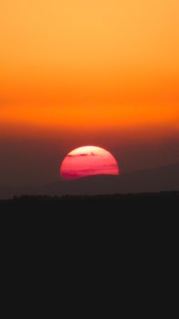 Breathtaking view of the sun setting over the hills of Madrid, casting a warm gradient across the sky.