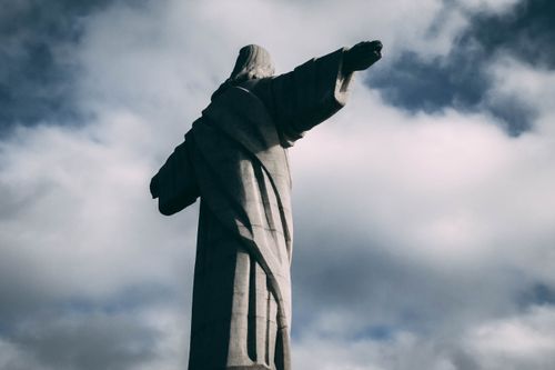 Free A view of the Christ the Redeemer statue in Rio de Janeiro captured from behind against a dramatic cloudy sky. Stock Photo
