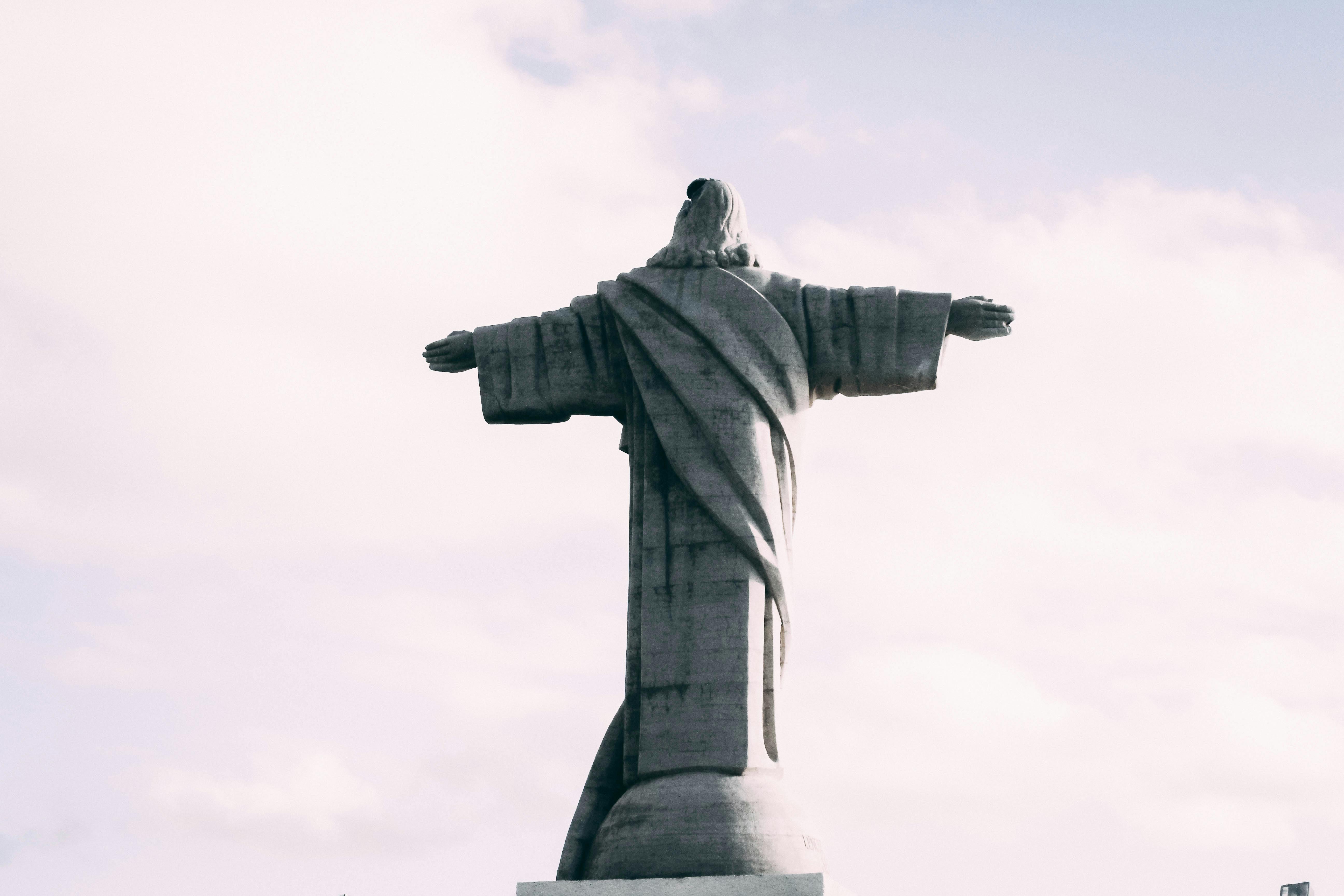 Back view of Christ the Redeemer statue in Rio de Janeiro against a cloudy sky.