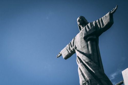 Free Iconic Christ the Redeemer statue with arms outstretched against a clear blue sky. Stock Photo