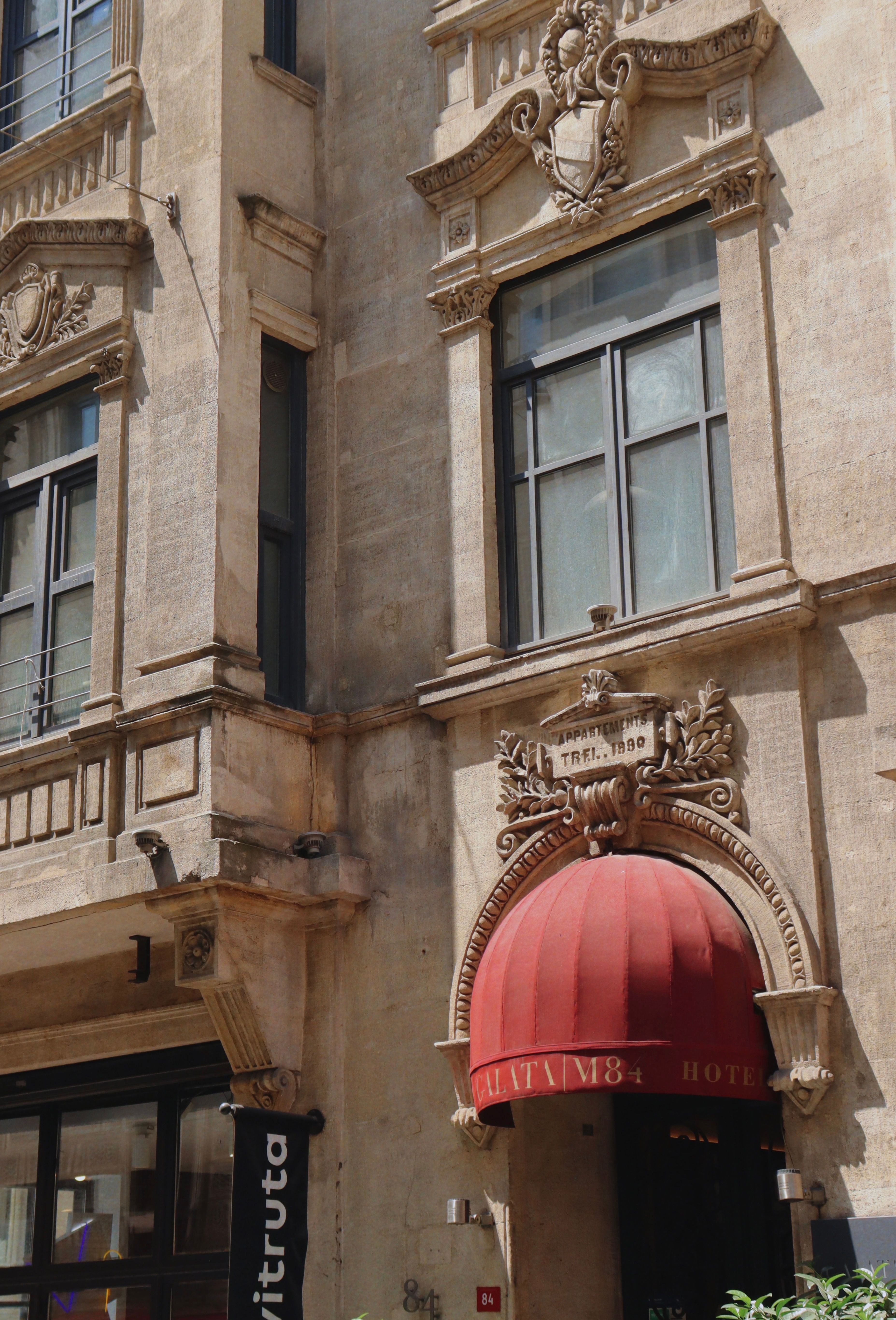 Façade d'un immeuble de copropriété ancien avec store et fenêtres en pierre.