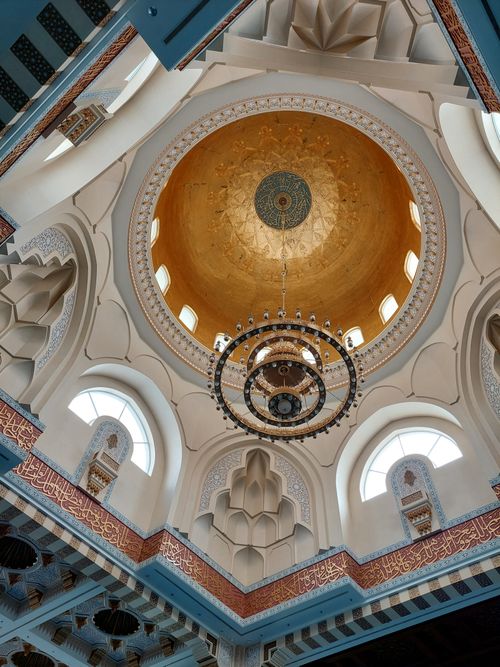 Free Intricate mosque interior featuring a golden dome and elegant chandelier. Captures architectural beauty. Stock Photo
