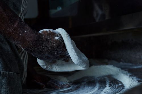 Free Close-up of a baker's hands kneading dough in a dimly lit kitchen setting. Stock Photo