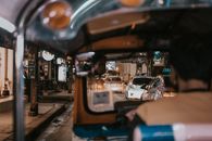 Experience the bustling night city view from the rear of a tuk-tuk, surrounded by cars and lights.