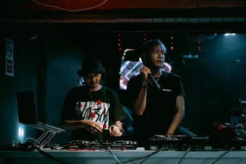 Two Men Standing behind a Console in a Nightclub 