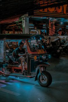 Atmospheric urban scene capturing a tuk-tuk at night in Bangkok's lively streets.