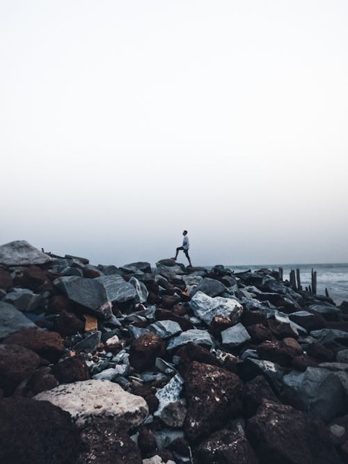 Man Standing on Rocks on Seashore
