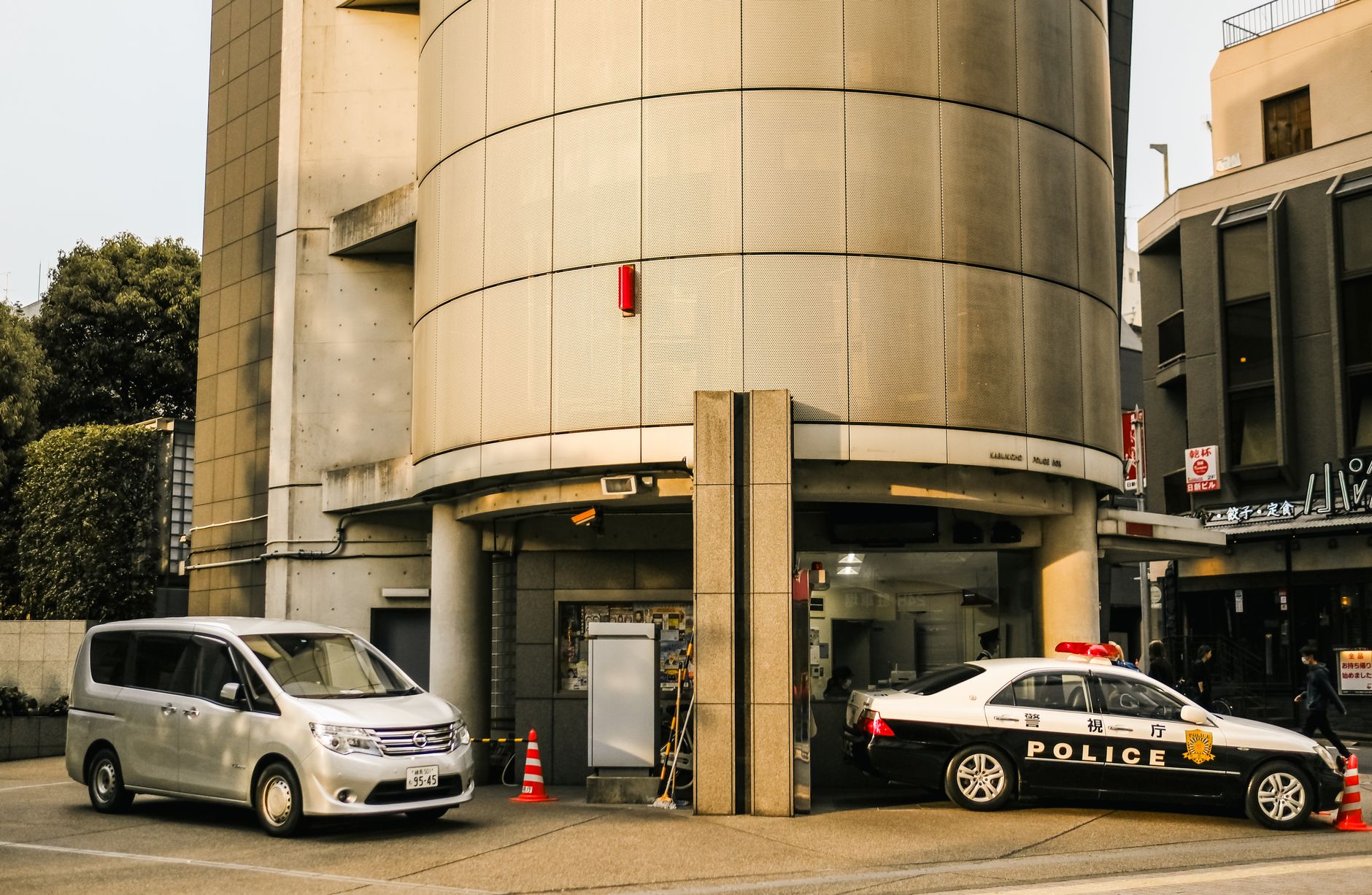 Street view featuring police and Nissan vehicles parked by a modern building.
