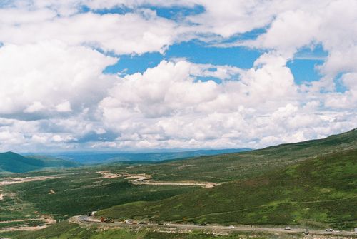 Free A breathtaking aerial view of green hills and roads under a dramatic cloudy sky, perfect for nature lovers. Stock Photo