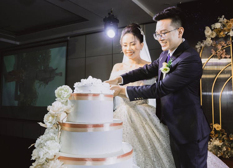 Smiling Bride And Groom Cutting Wedding Cake