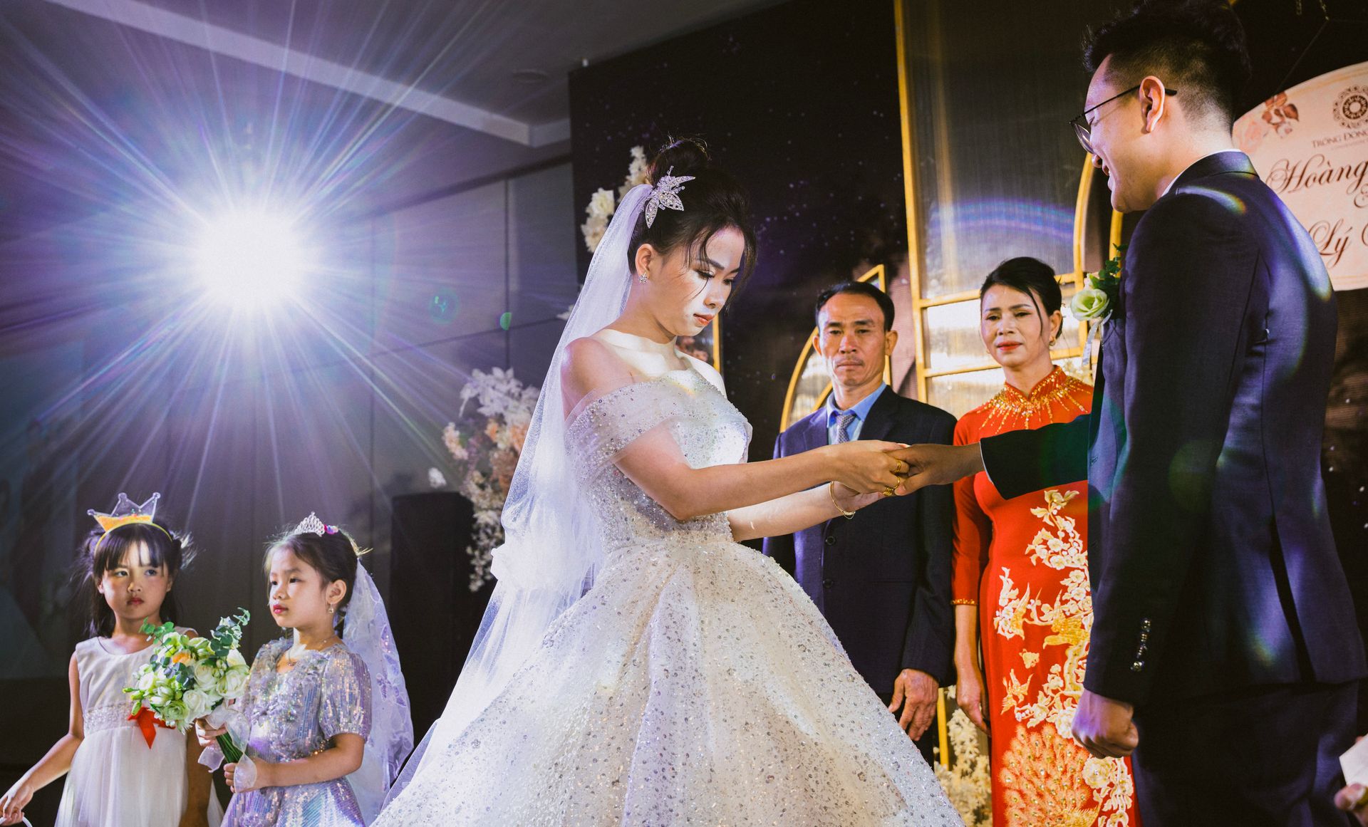 Bride and groom exchange vows in a traditional Asian wedding ceremony with children as flower girls.
