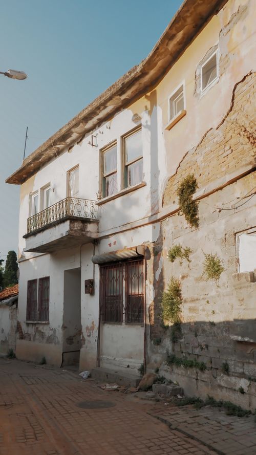 Free A deserted old house showing signs of decay and weathering on a sunlit street. Stock Photo