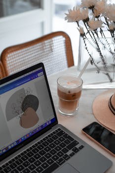 A stylish home office setup with a laptop, iced coffee, and neutral decor.