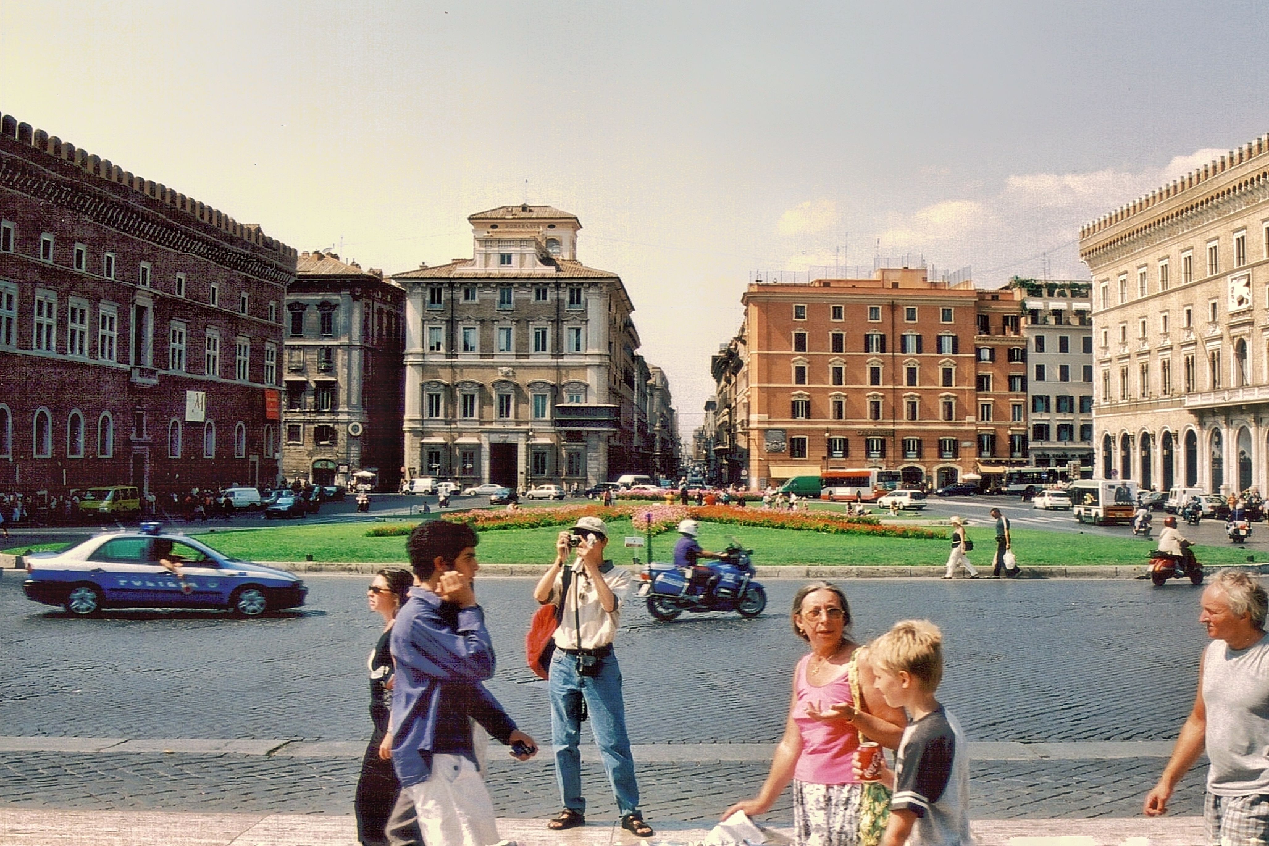 A bustling street view of Rome with people, cars, and classic Italian architecture