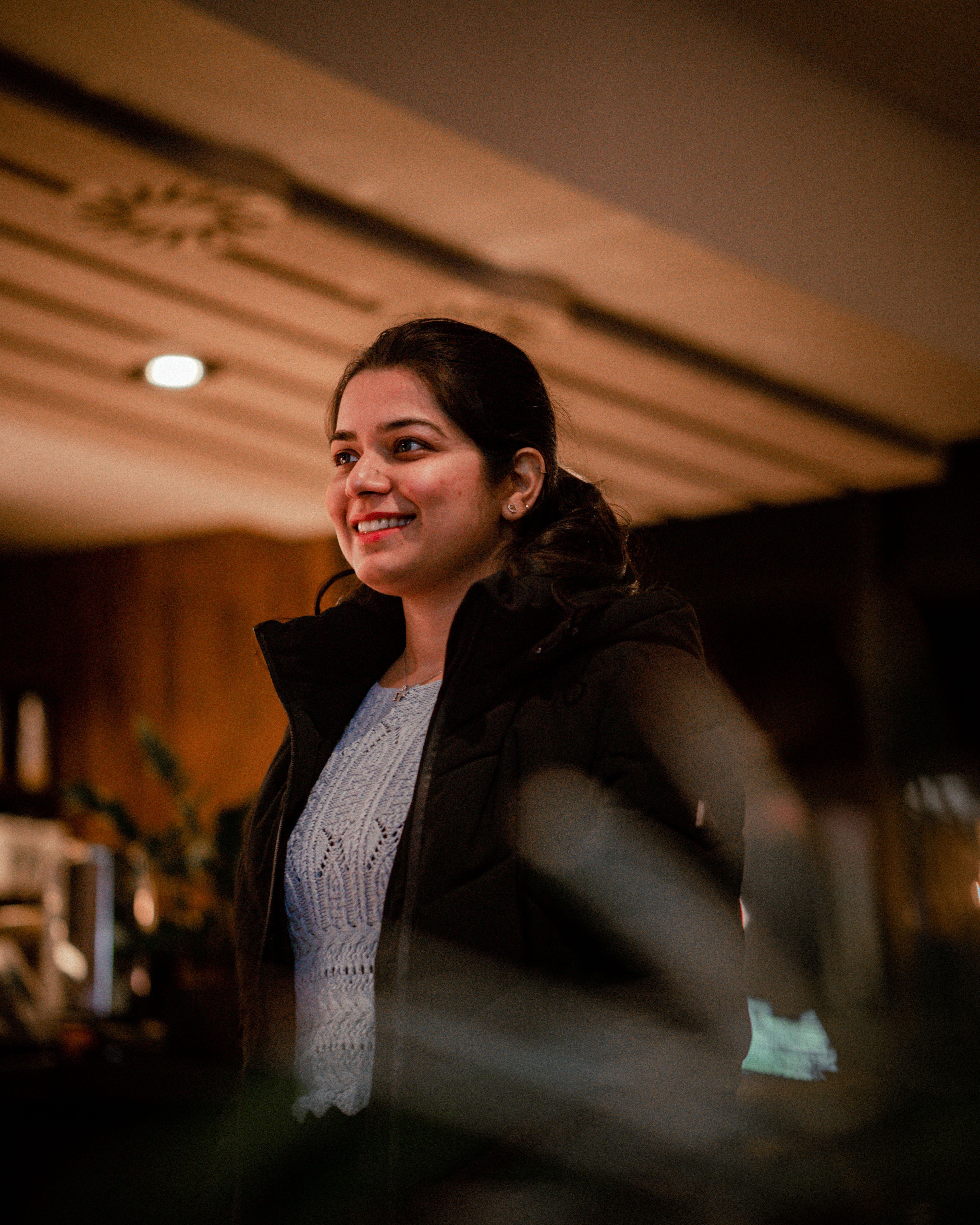 A woman smiling warmly and looking relaxed in soft natural light.
