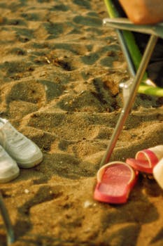 A serene beach setting with red flip flops and a green chair, ideal for a relaxing vacation.