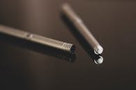 特写图像展示了一支光滑金属笔在反光表面上，突显现代设计